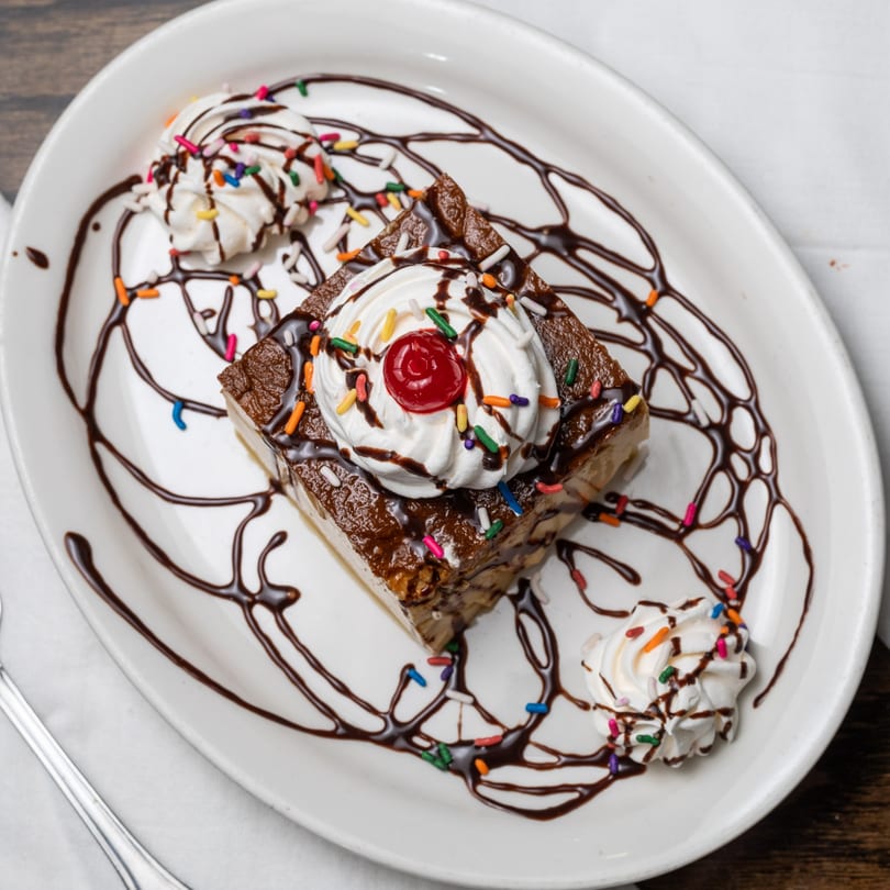 Mi Casita's dessert, a chocolate cake slice with whipped cream, cherry, and colorful sprinkles.