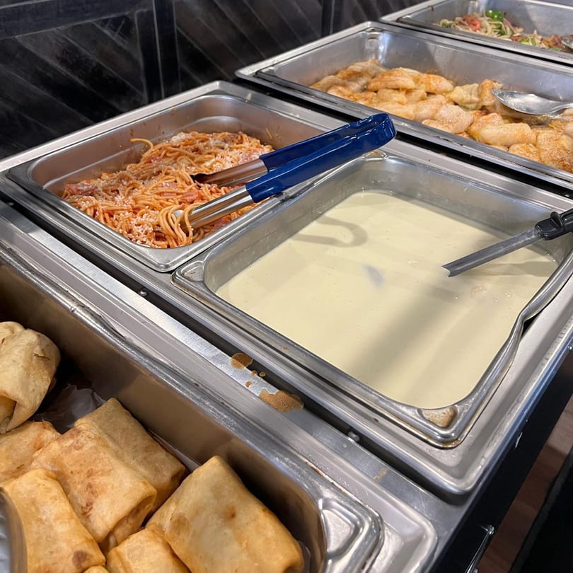 Buffet line with trays of spaghetti, creamy soup, chicken, and fried burritos at Mi Casita.